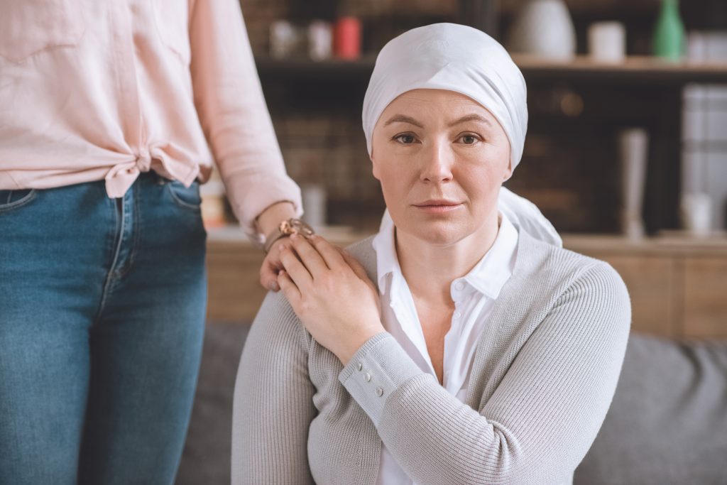 žena podporuje chorú matku na rakovinu v šatke pri pohľade na fotoaparát